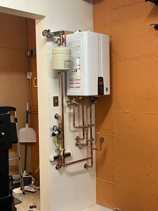 Plumbing technician inspecting water heater connections in Tilton